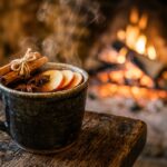 Ultra close-up macro of steaming hot spiced apple cider and crackling stone hearth fireplace in a Cotswolds inn