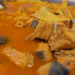 Ultra close-up macro of traditional Icelandic fish stew simmering with cod and winter herbs