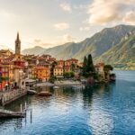 Panoramic view of Varenna waterfront on Lake Como Italy with pastel houses church tower and mountains