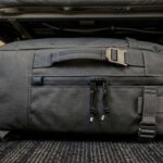 Ultra close-up macro of minimalist 28L travel backpack stowed beneath airline passenger seat