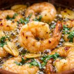 Ultra close-up macro of sizzling Spanish garlic prawns in terracotta cazuela dish with olive oil and parsley