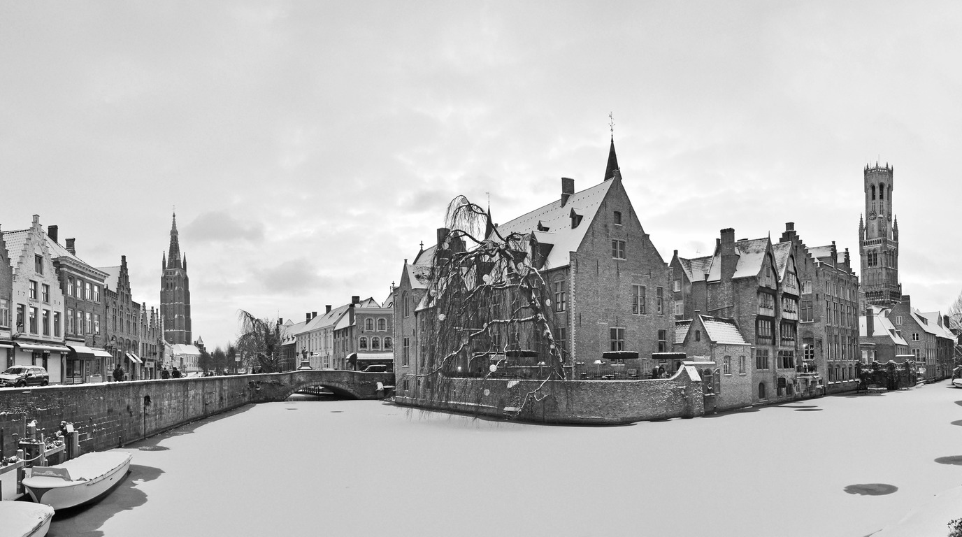 Picturesque winter view of the Rozenhoedkaai canal in Bruges Belgium with historic medieval brick houses and the Belfry tower reflected in calm water