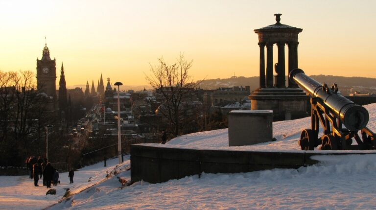 Panoramic winter sunset view from Calton Hill over the historic spires and Edinburgh Castle in Scotland with Dugald Stewart Monument in the foreground