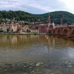Panoramic view of Heidelberg Castle perched on forested hills above the Neckar River and the Old Bridge in winter