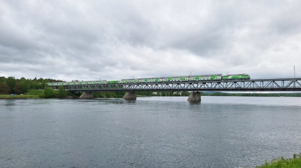 Green and white Finnish double-decker VR night train Santa Claus Express crossing the snowy Ounaskoski bridge into Rovaniemi Lapland in winter