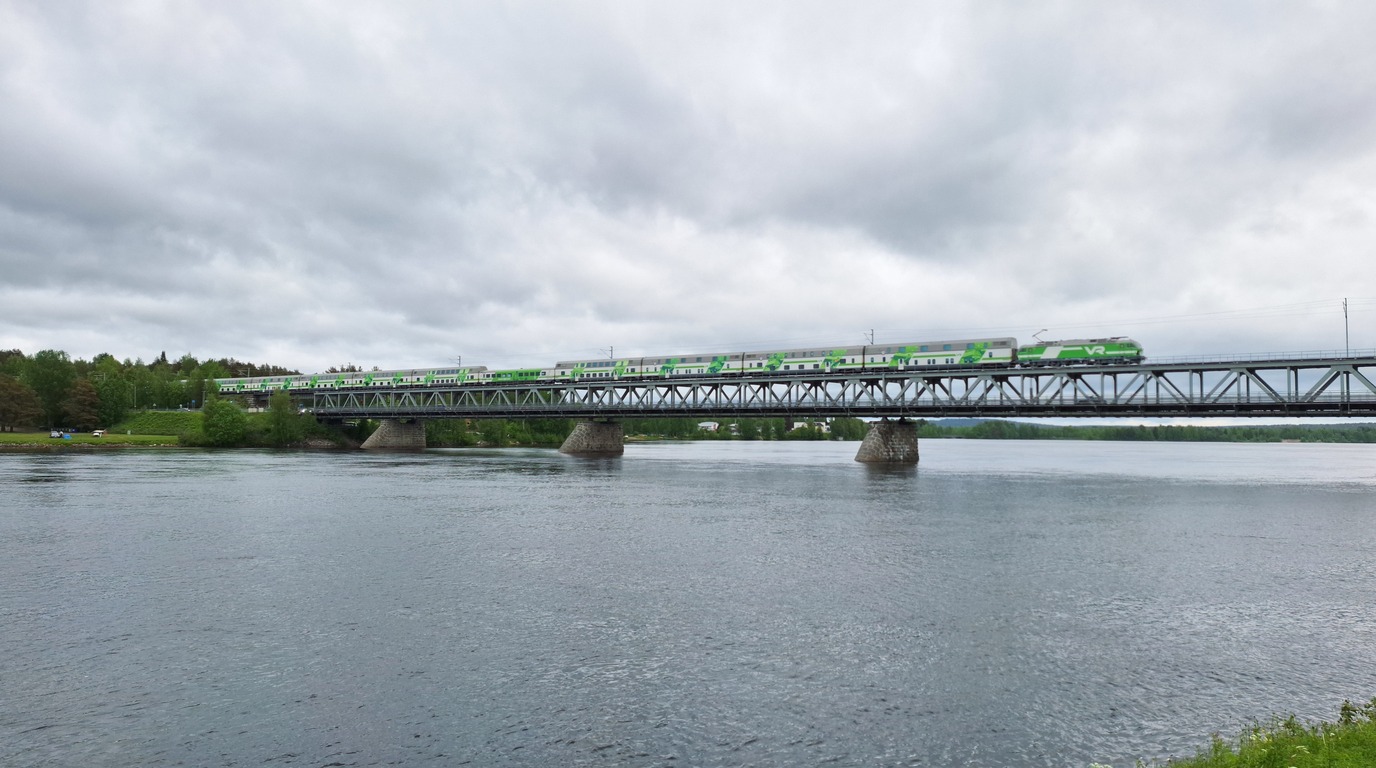 Green and white Finnish double-decker VR night train Santa Claus Express crossing the snowy Ounaskoski bridge into Rovaniemi Lapland in winter