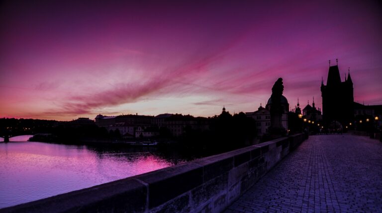 Panoramic winter view of Charles Bridge at pink sunrise over the misty Vltava river with Prague Castle in Czech Republic