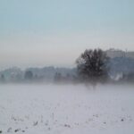 Panoramic winter view of Hohensalzburg Fortress high on a snowy cliff above Baroque church domes and historic rooftops of Salzburg Austria