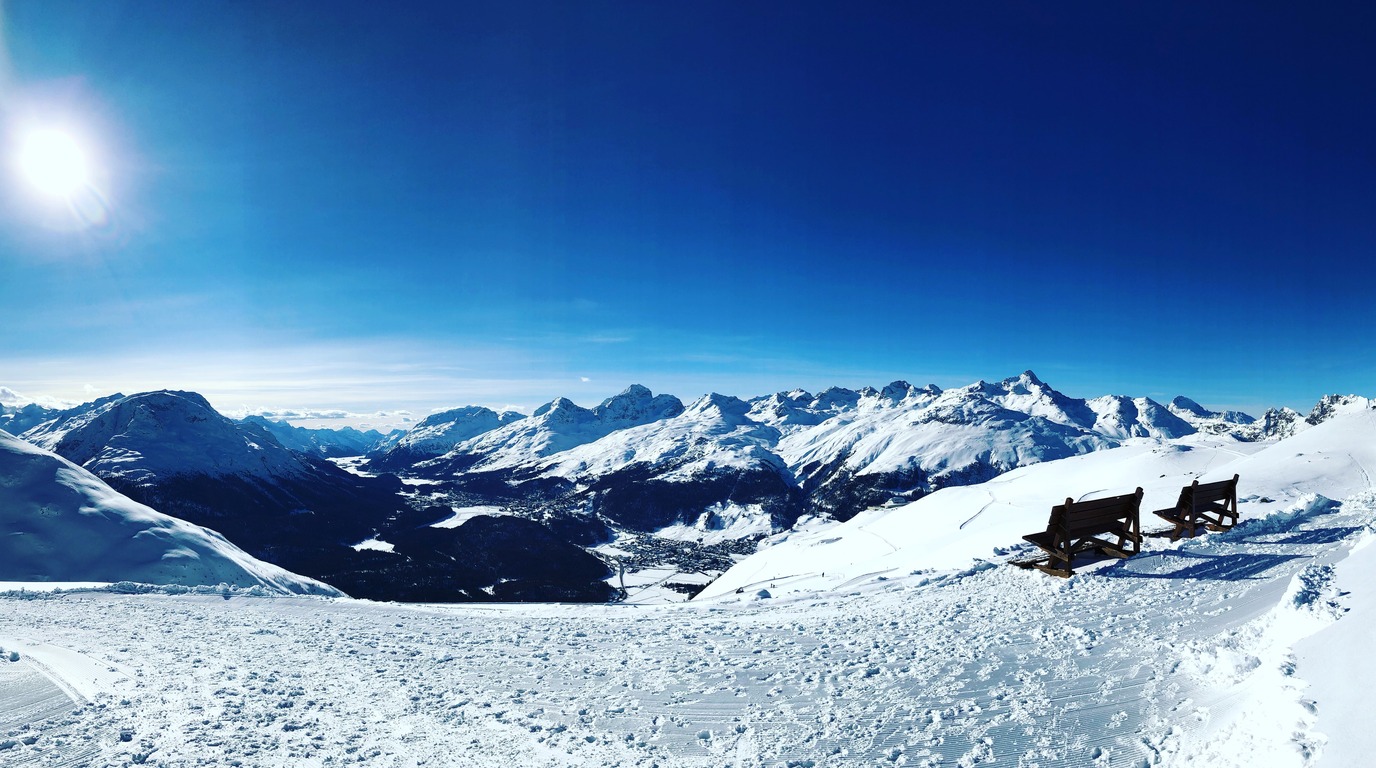 Panoramic alpine view of St. Moritz frozen lake and snow-covered Engadin mountains in winter