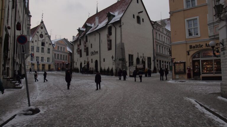 Panoramic winter view of Tallinn Old Town in Estonia with medieval defensive walls red-tiled towers and Gothic church spires covered in fresh snow